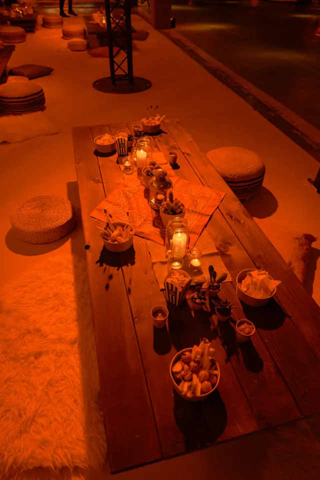 Ambiance western chaleureuse avec tables en bois, bougies et coussins au sol pour un moment convivial entre collègues.