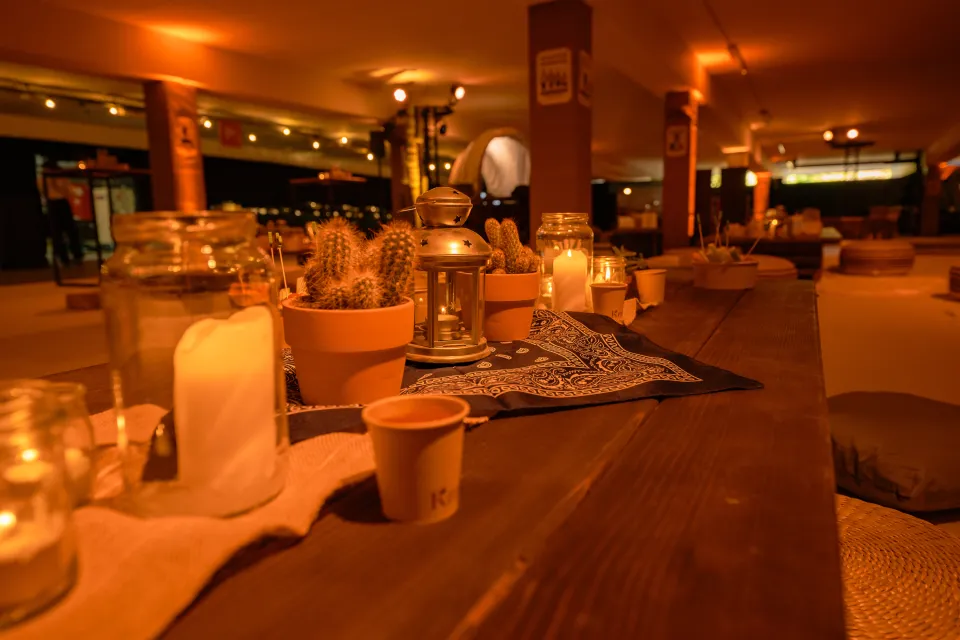 Ambiance western chaleureuse avec tables en bois, bougies et coussins au sol pour un moment convivial entre collègues.
