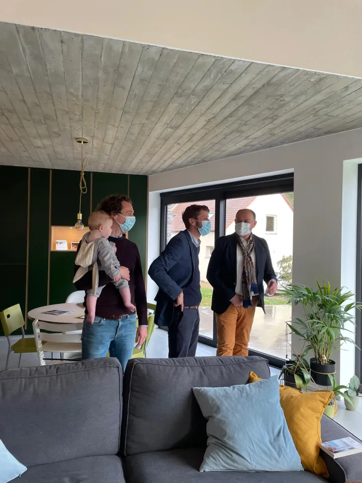 Visite d’une maison contemporaine lors du week-end Maisons & Architectes, avec plusieurs personnes masquées discutant près des baies vitrées