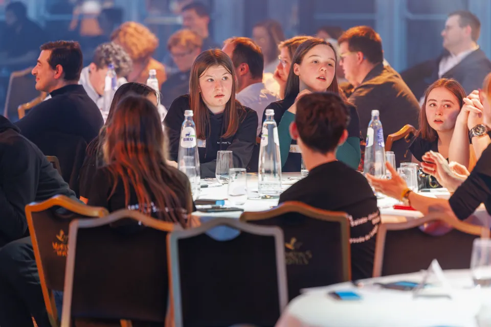 Jeunes participants réunis autour de tables rondes lors de L’Odyssée de l’Objet, écoutant attentivement les annonces de la cérémonie dans une ambiance studieuse et lumineuse.